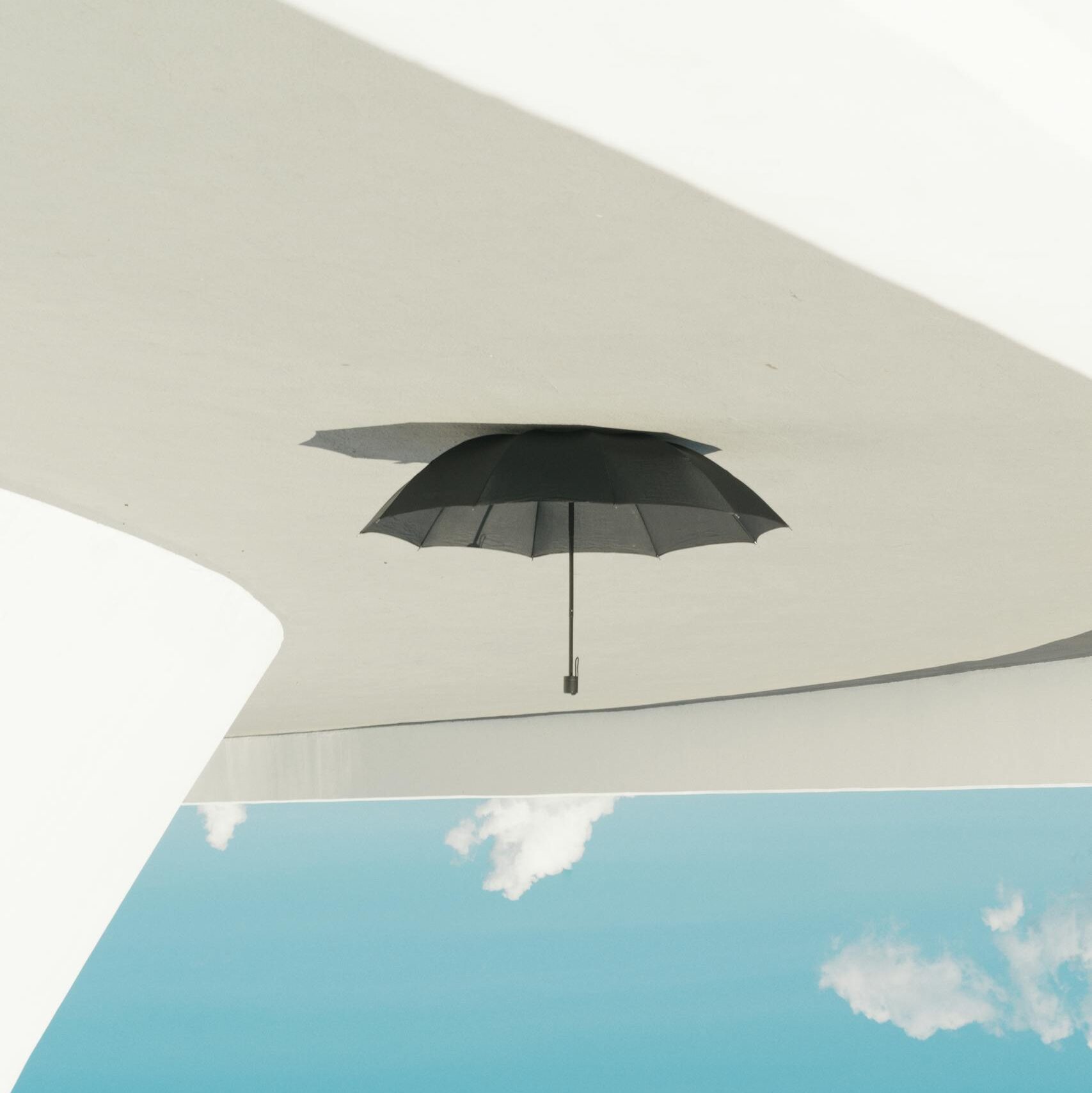 A black umbrella hanging upside down against a clear blue sky, creating a unique and abstract outdoor scene in Brasília, Brazil.